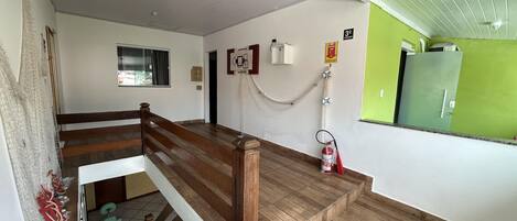 Una escalera con peldaños de madera y barandilla blanca que conduce a una habitación con pared verde y una puerta.