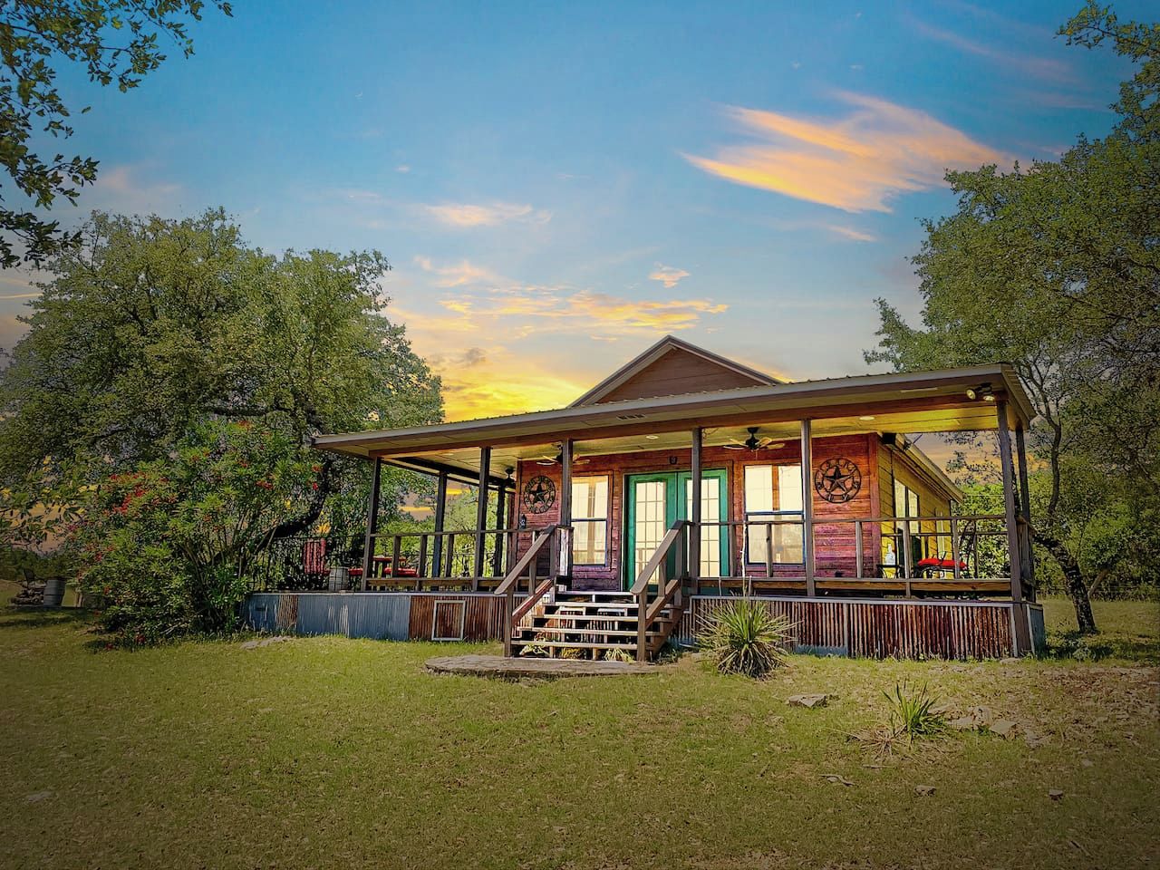 Eine Holzhütte mit Veranda, umgeben von Bäumen und Gras.
