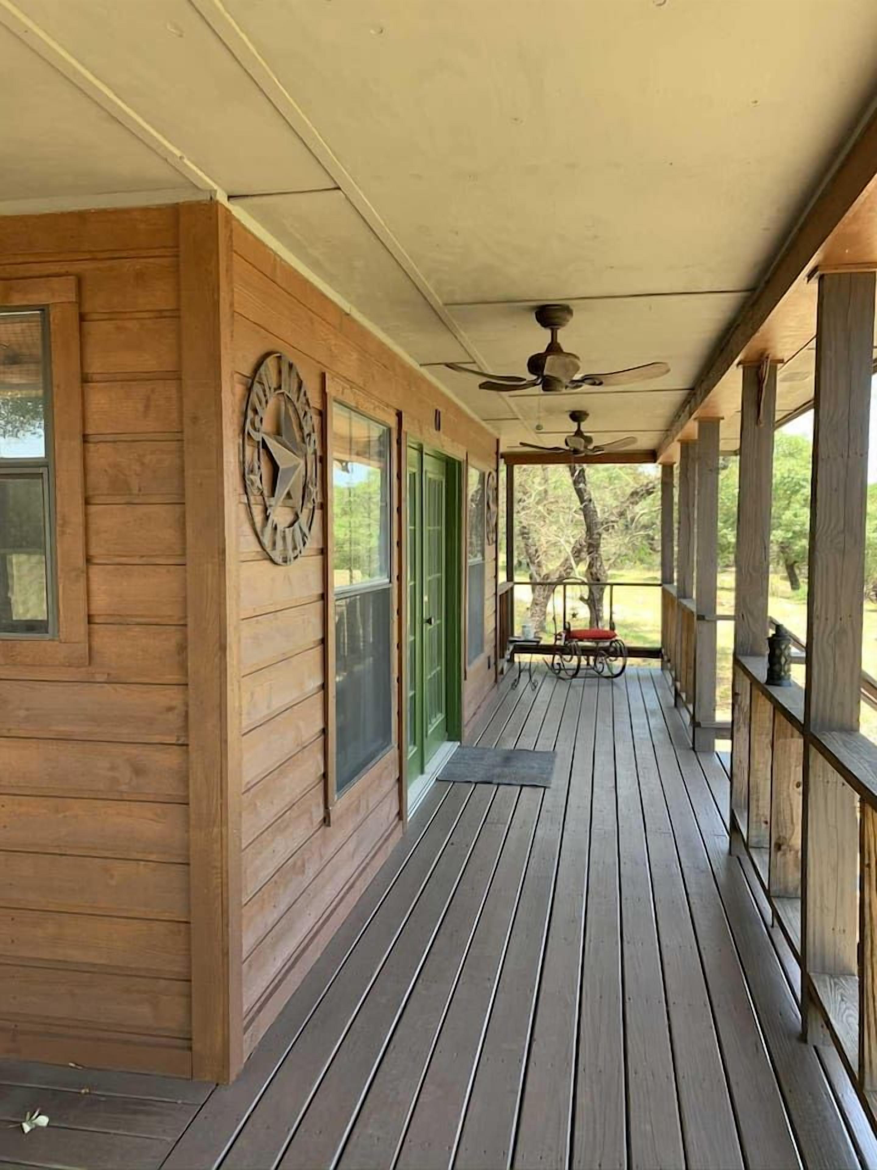 A wooden porch with a ceiling fan, a clock, and a bicycle.