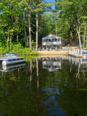 A lakeside cabin with a dock, surrounded by dense forest.