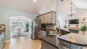 A modern kitchen with a large island, stainless steel appliances, and a dining area with a view. - BEACH LIFE, BEST LIFE oversized pool, 2 min walk to beach; close to DT, PETS OK (St. Augustine)