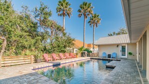 A swimming pool with a tiled deck, surrounded by palm trees and a wooden fence. - BEACH LIFE, BEST LIFE oversized pool, 2 min walk to beach; close to DT, PETS OK (St. Augustine)