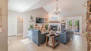 A spacious living room with a sectional sofa, a fireplace, and a television. - BEACH LIFE, BEST LIFE oversized pool, 2 min walk to beach; close to DT, PETS OK (St. Augustine)