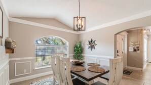 A dining area with a wooden table, white chairs, and a decorative ceiling light. - BEACH LIFE, BEST LIFE oversized pool, 2 min walk to beach; close to DT, PETS OK (St. Augustine)