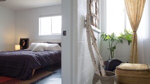 A bedroom with a bed, a window, a wall-mounted plant, and a woven basket. - The Ridge at Joshua Tree (Joshua Tree)