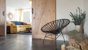 A modern living room with a sofa, a unique black chair, and a decorative plant. - The Ridge at Joshua Tree (Joshua Tree)