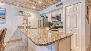 Kitchen features a granite countertop, stainless steel appliances, and white cabinetry.