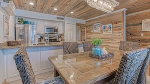 Enjoy meals in the kitchen with stainless steel appliances and a granite countertop, surrounded by a dining area with a glass table and woven chairs.