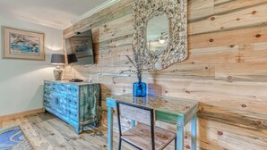 Une pièce avec un mur en bois, un miroir, un vase bleu, une télévision et un tableau encadré.