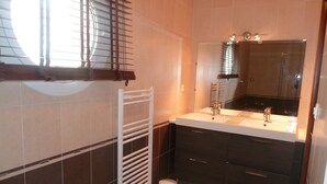 A bathroom with a white sink, dark cabinets, a mirror, and a window with blinds. - GUIDEL BEACHES HOLIDAY HOME NEAR THE BEACHES (Guidel)