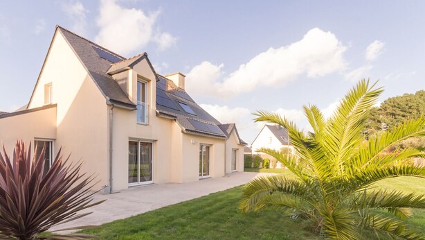 A modern house with a sloped roof, solar panels, and a well-maintained lawn with tropical plants. - GUIDEL BEACHES HOLIDAY HOME NEAR THE BEACHES (Guidel)