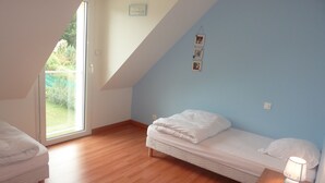 A bedroom with a sloped ceiling, a bed with white bedding, a bedside lamp, and a small table. - GUIDEL BEACHES HOLIDAY HOME NEAR THE BEACHES (Guidel)