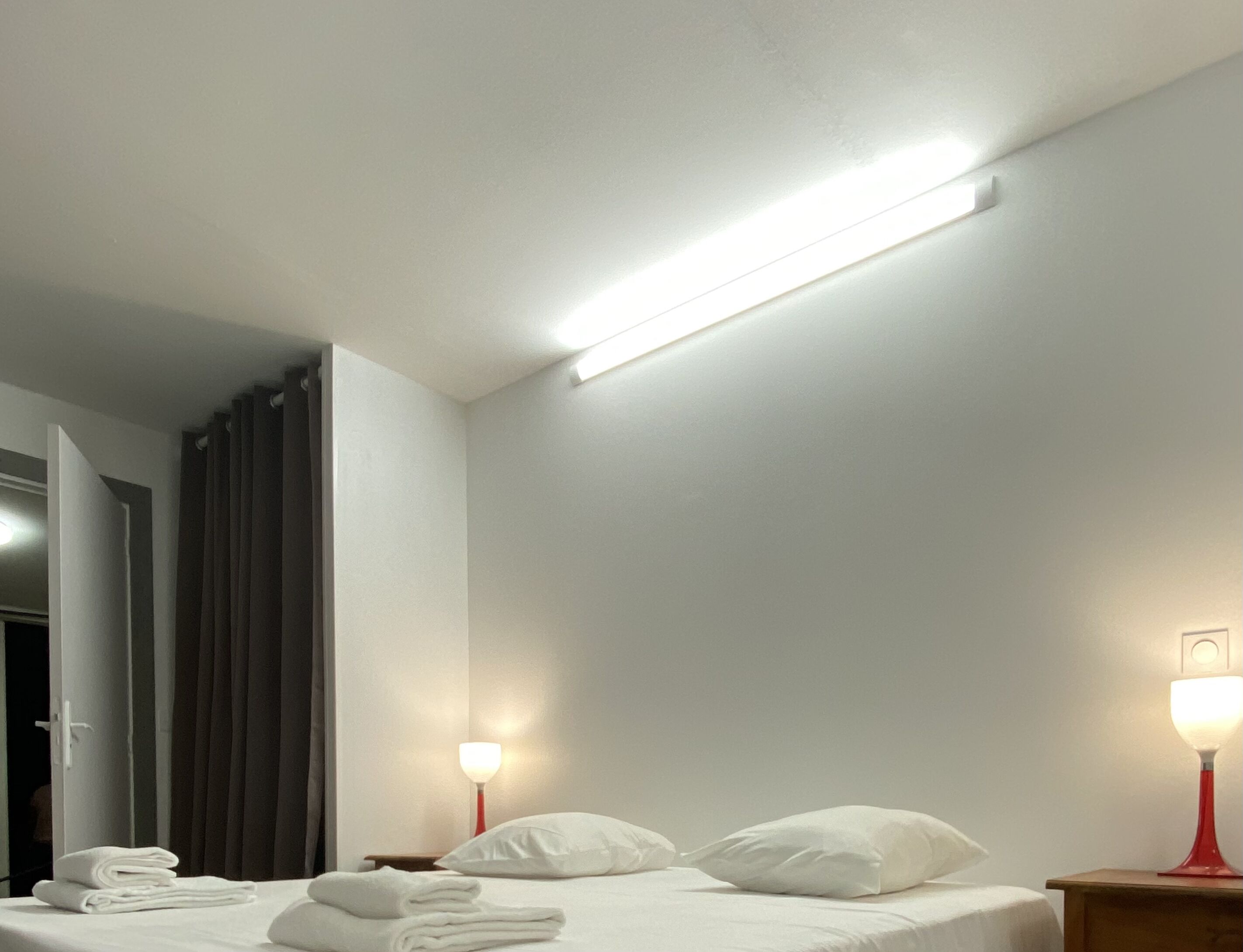 Une chambre d’hôtel avec un lit, deux lampes de chevet, un miroir et une porte.