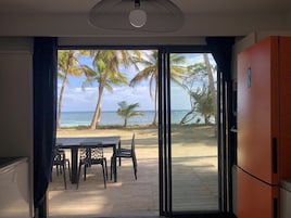 Una habitación con vista a la playa, una mesa de comedor con sillas y un ventanal grande.