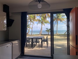 Una habitación con vista a la playa, una mesa de comedor con sillas y un ventilador de techo.