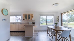 A modern kitchen with a central island, wooden cabinets, and a dining area with a table and chairs.