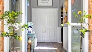 A clean, well-lit entrance with a white door, a sign above it, and a small table with decorative items. - Fair Views over the Inlet (Sussex Inlet)