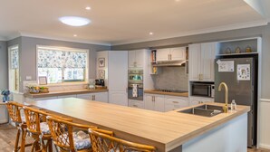 A modern kitchen with a central island, white cabinetry, and stainless steel appliances. - Fair Views over the Inlet (Sussex Inlet)
