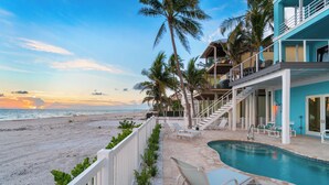 A beachfront property with a swimming pool, lounge chairs, and a view of the ocean. - Beachfront Vacation Home | Heated Pool | Panoramic Gulf Views (Bonita Springs)