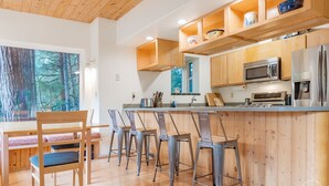 Eine moderne Küche mit Holzschränken, Edelstahlgeräten und einer Bar mit Barhocker.