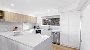 Una cocina moderna con una isla central, electrodomésticos de acero inoxidable y un ventanal que proporciona luz natural.