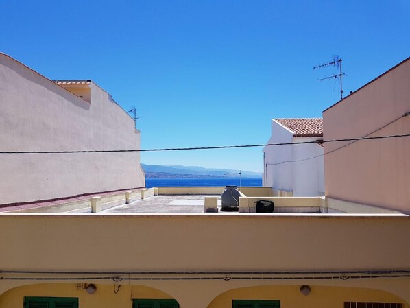 Una terraza en la azotea con vistas despejadas al mar y montañas a lo lejos.