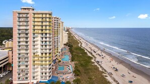 A high-rise hotel with multiple balconies, a beach, and a swimming pool complex. - Coastal Beachfront Paradise! Resort Style Amenities with a BRAND NEW KITCHEN!! (North Myrtle Beach)