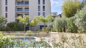 Ein Pool, umgeben von Grünflächen, mit einem mehrstöckigen Gebäude und Balkonen.