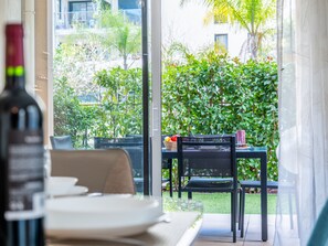 Un rincón de comedor con una mesa dispuesta para dos, una silla y una botella de vino.