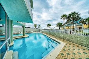A swimming pool with a stone wall and palm trees in the background.