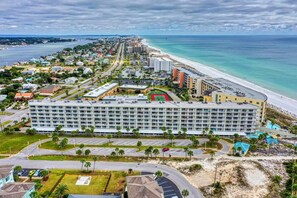 A large hotel with multiple floors, a parking lot, and a beachside location.