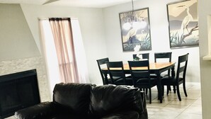 A living room with a black leather sofa, a dining table with chairs, and a fireplace. - Rancho Viejo Getaway Condo (Rancho Viejo)