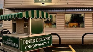 A diner with a green and white striped awning, a 'DINER' sign above, and a 'DINER DELIVERY' service with a phone number. - Rancho Viejo Getaway Condo (Rancho Viejo)