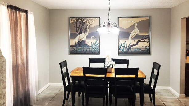 A dining area with a wooden table and black chairs, surrounded by two framed artworks depicting birds and nature scenes. - Rancho Viejo Getaway Condo (Rancho Viejo)