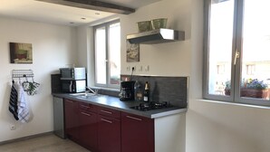 Una cocina moderna con microondas integrado, estufa y lavaplatos. Hay una ventana con vistas al exterior y un pequeño estante sobre la estufa.