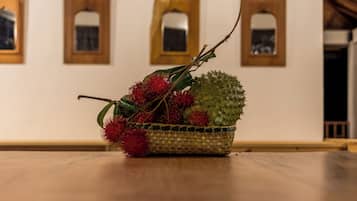 Uma cesta de vime com uma fruta verde e frutos vermelhos e espinhosos sobre uma mesa de madeira.