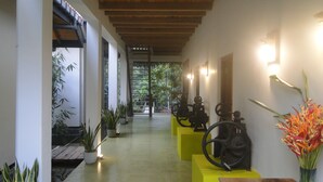 Un pasillo con vigas de madera, plantas en macetas y una exhibición de engranajes mecánicos.
