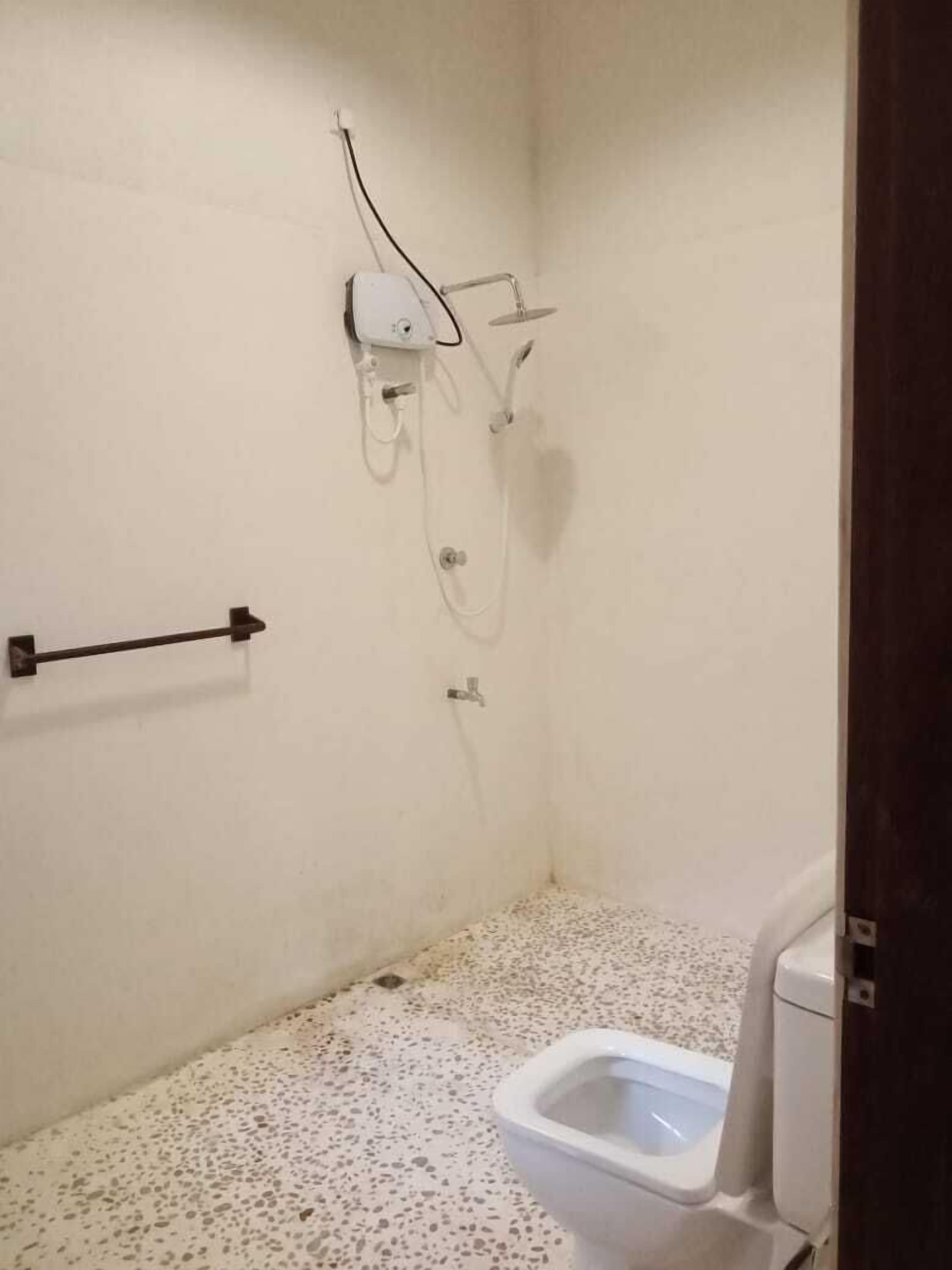 A small, basic bathroom with a toilet, a shower, and a towel rack.
