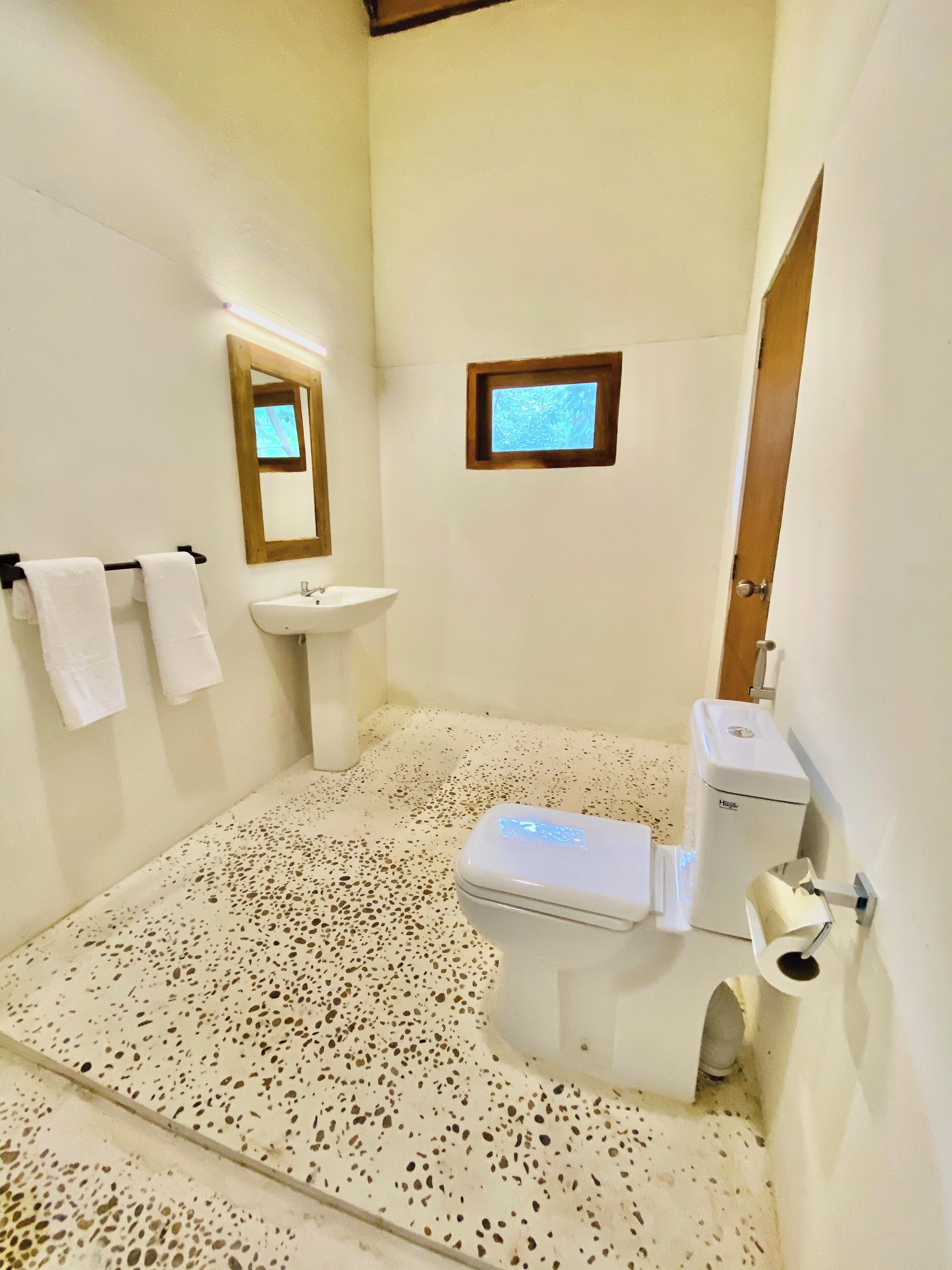 A bathroom with a white sink, a toilet, and a small window.