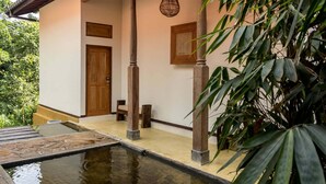 Un edificio tradicional con puerta de madera, una pequeña zona de estar y una fuente en la parte delantera.