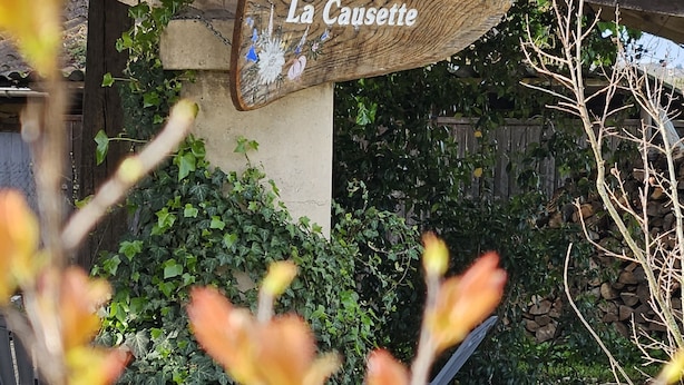 A rustic building with a tiled roof and a wooden sign that reads "La Causette."