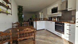 A modern kitchen with white cabinets, a wooden dining table, and a built-in oven.
