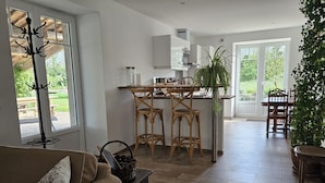A modern kitchen with a central island, wooden chairs, and a dining area with a table and chairs.