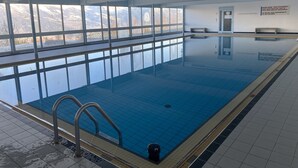 An indoor swimming pool with clear windows, a diving board, and a view of mountains. - Nendaz Centre Superbe Appartement 3 p. 75m2 Avec Piscine Parking et vue (Nendaz)