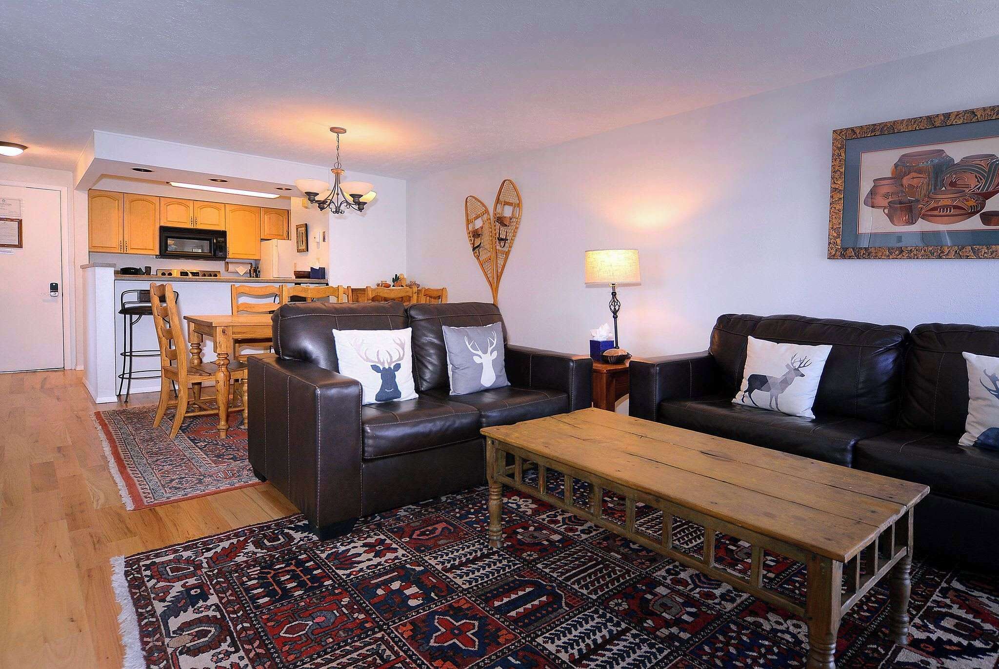 Een woonkamer met een bank, salontafel, een tapijtend met patroon, en een eethoek met stoelen en een tafel.