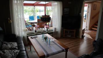 A living room with a wooden table, a sofa, and a TV.
