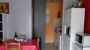 Cocina compacta con comedor, que incluye un microondas, horno y un refrigerador pequeño.