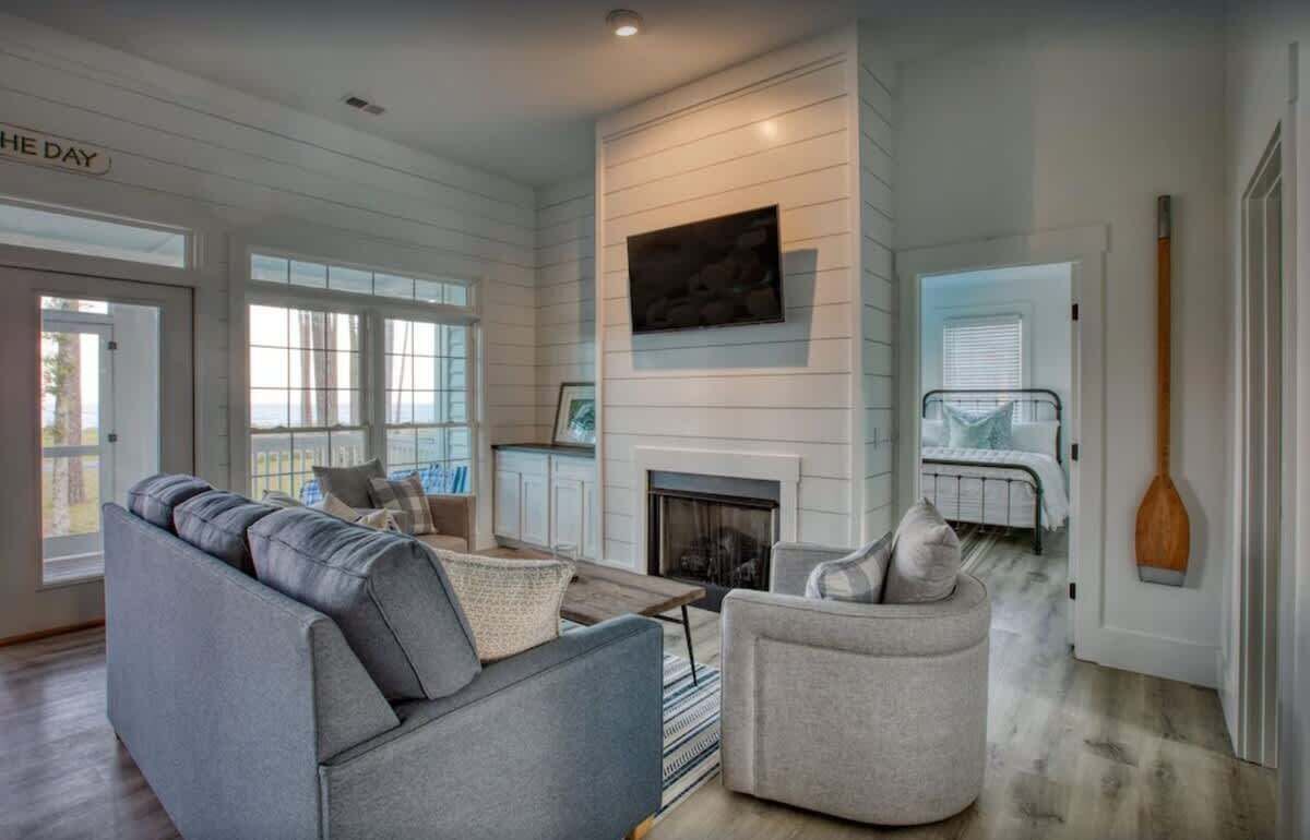 A modern living room with a fireplace, a sofa, a chair, and a view of the outdoors.