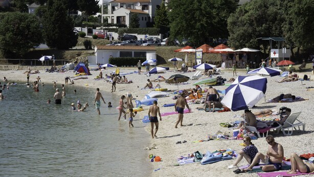 Une plage avec des parasols, des gens et des chaises de plage.