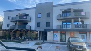 Un immeuble à plusieurs étages doté de balcons, d’une aire de stationnement et d’une voiture garée devant.